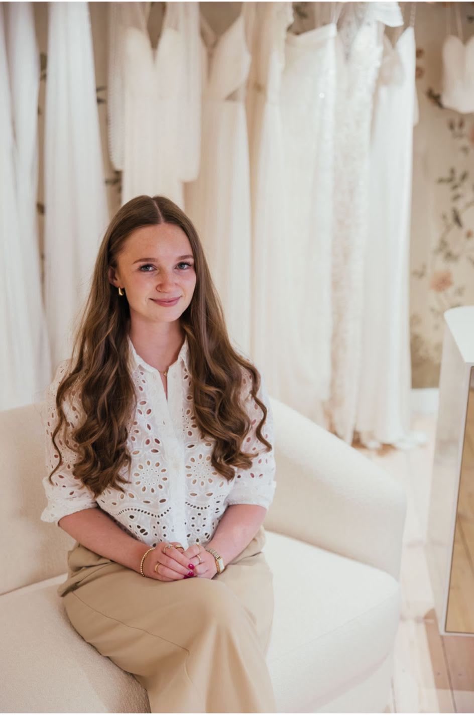Lia, designer and creative lead at Vowen, seated in a bridal studio surrounded by hanging wedding gowns