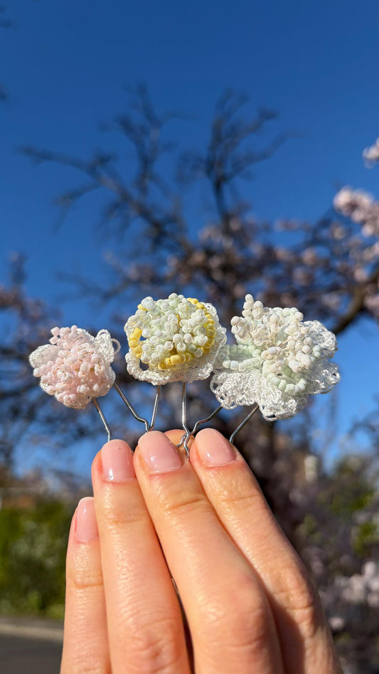 The three Blossom hair pins held up against a spring blossom tree