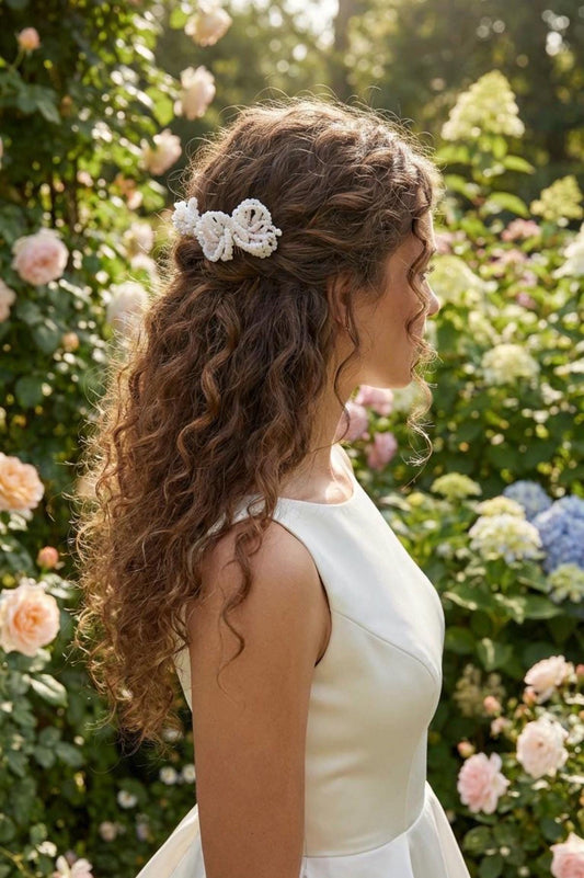 Bride wearing the Mabel hair comb in long curls, styled half-up in a summer rose garden