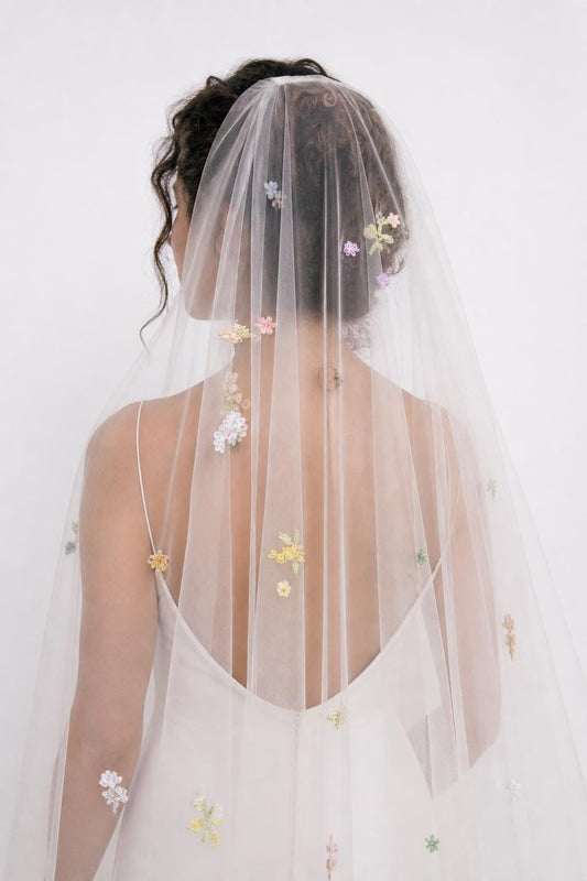 Vera veil worn over loose curls in the studio, showing its scattered floral embroidery
